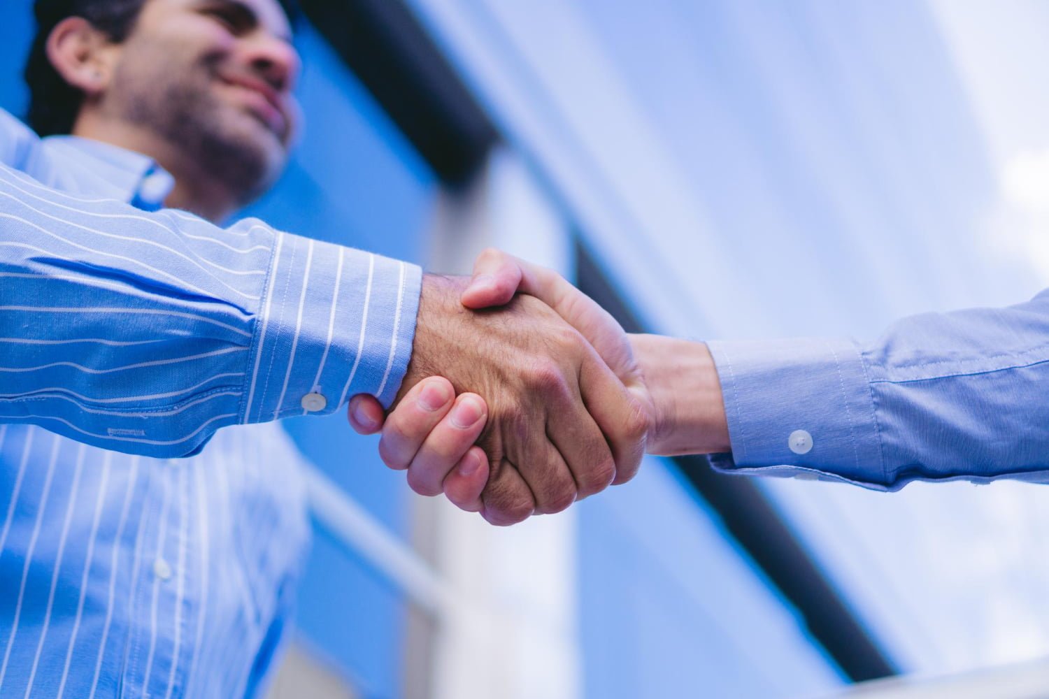 closeup-detail-handshake-with-young-man-blurred-wearing-shirt-smiling