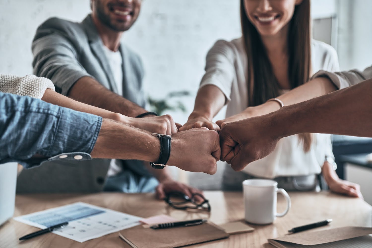 success-close-up-business-colleagues-holding-fists-together-symbol-unity-smiling-while-working-board-room